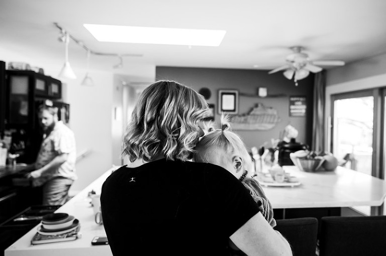 black and white image of mom and toddler daughter snuggling in their kitchen by denver, colorado documentary photography company real life photo co