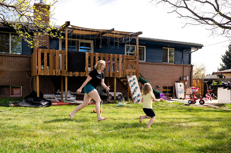 mom chasing young daughter in their backyard by denver, colorado documentary photography company real life photo co