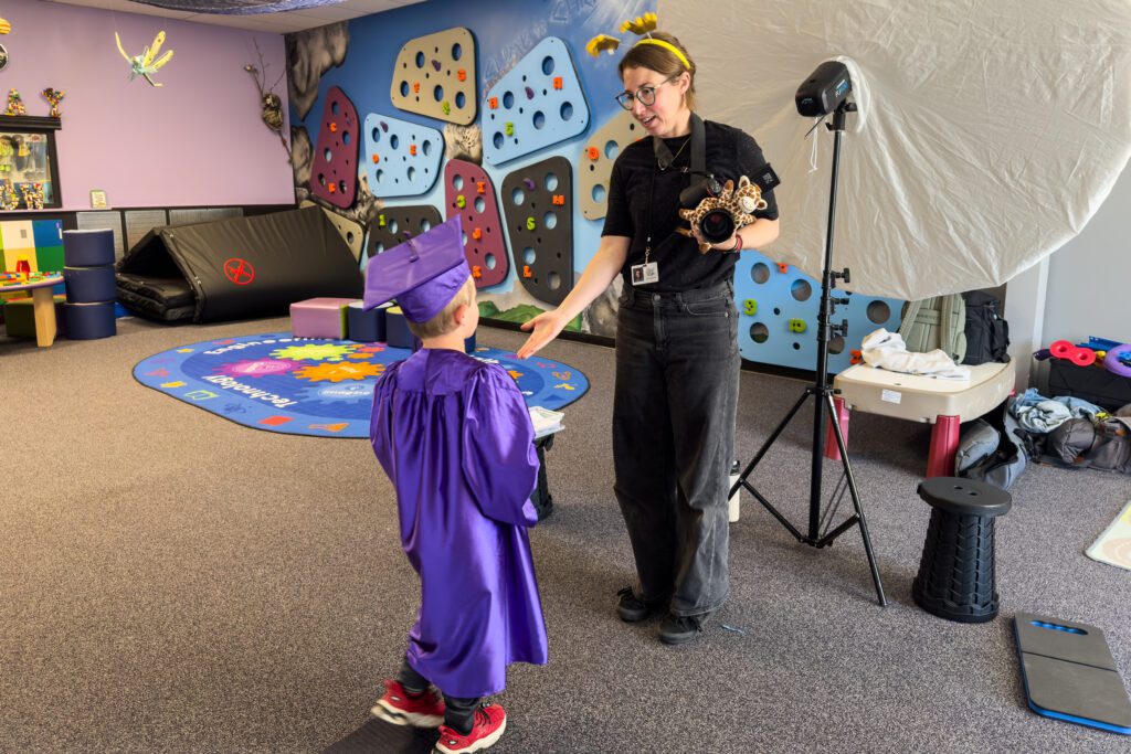 School photographer giving a kindergarten cap and gown student a five after completing their school picture day photos.
