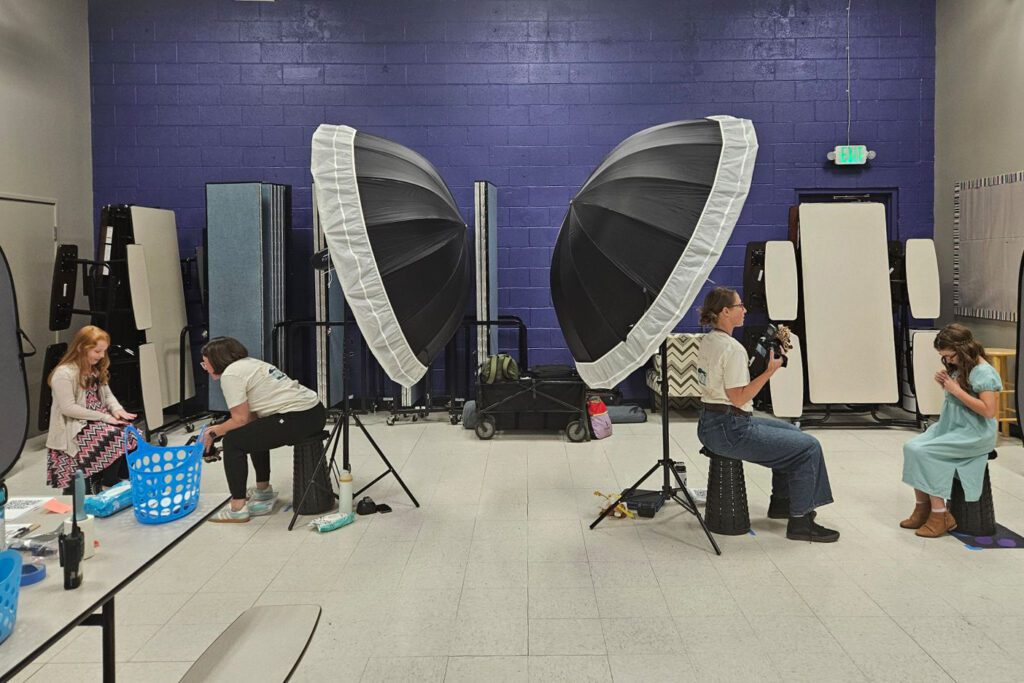 Two photographers working together, back to back, to photograph students at a school for picture day.